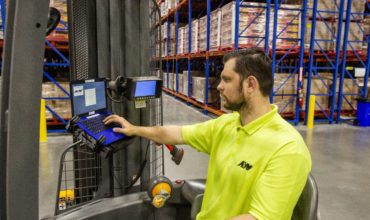 Warehouse worker using management system technology on the forklift