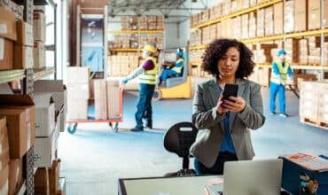 Warehouse manager reviewing inventory data on mobile device in modern distribution facility